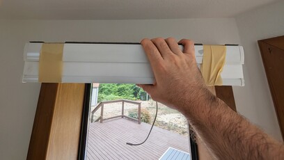 19-inch motorized blind taped on both sides with blue painter&rsquo;s tape, ready for cutting with a metal saw